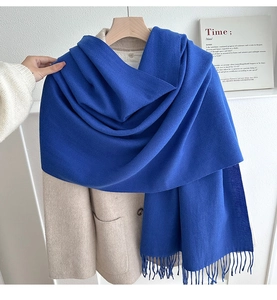 Detail of royal blue fringe scarf paired with a beige wool coat for winter styling