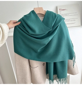 Close-up of forest green tassel scarf texture paired with elegant beige wool coat