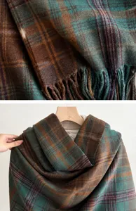 Dettaglio macro della sciarpa a quadri che mostra maglia marrone e verde e le frange