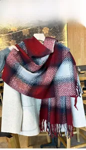 Close-up of thick winter gradient plaid scarf with fringe on a beige wool coat