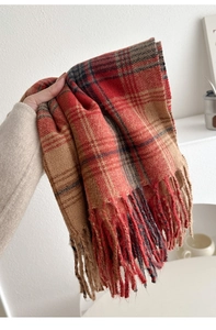 Detail des rot-khaki karierten Strickschals mit weicher Textur und langen Fransenquasten