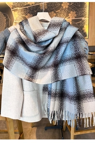 Detail of blue and brown checkered thick winter scarf with fringe on a beige coat