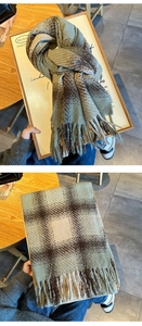 Detail of sage green and brown plaid scarf featuring thick fringe and cozy plush texture