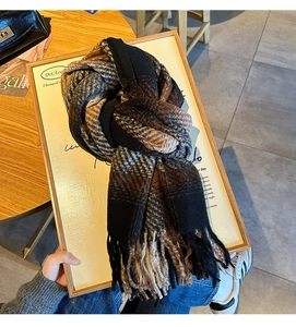 Close-up of thick winter scarf with brown gradient plaid pattern and long tassel details