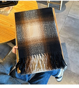 Detail view of thick winter scarf with gradient brown grid pattern and tassel trim