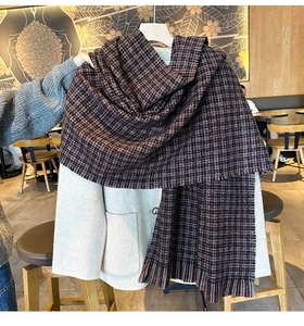 Détail d'une écharpe en maille pied-de-poule gris foncé avec franges et manteau en laine blanc