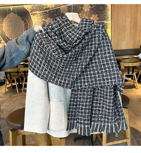 Détail d'une grande écharpe en maille à carreaux noirs et blancs avec des franges