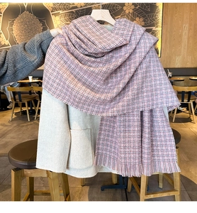 Détail d'une écharpe en maille cachemire à carreaux rose et gris avec des franges