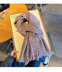 Gros plan détaillé d'une écharpe en maille à carreaux rose et gris avec franges