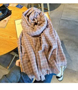 Détail d'une écharpe en maille à carreaux roses et gris avec finitions à franges