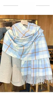 Detail eines blau-weiß karierten Schals mit Fransen an einem Holzbügel