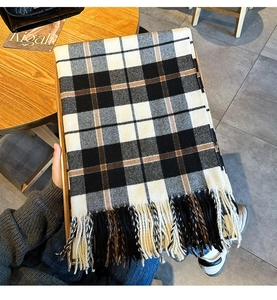 Detailansicht eines dicken Strickschals mit schwarz-weiß-braunen Quastenfransen