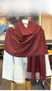 Detailed view of thick red and blue plaid scarf with fringe on a light wool coat