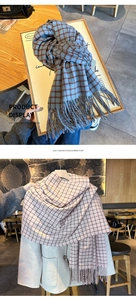 Detail of red and blue plaid imitation cashmere scarf with tassels on beige coat