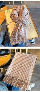 Detail of pink and brown checkered scarf with long fringe in a cozy cafe setting