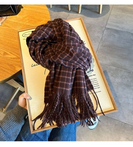 Close-up of thick red plaid scarf with decorative tassels on a wooden display
