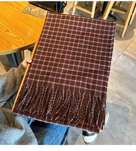 Detailed view of the red and brown plaid scarf featuring soft knit texture and fringe edge