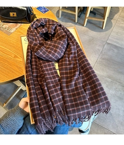 Close-up of brown plaid scarf with tassels on a wooden table for winter fashion