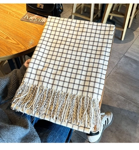Detail shot of classic black and white checkered knit scarf with soft fringe trim