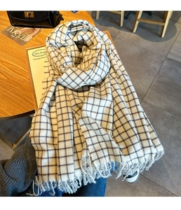 Detailed view of a black and white checkered scarf with soft fringe on a wooden table