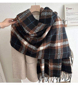 Detailed texture of thick vintage plaid scarf with tassels on beige wool coat