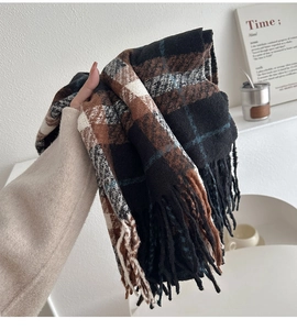 Detail of colorful plaid scarf with long fringe showing thick knitted texture and pattern