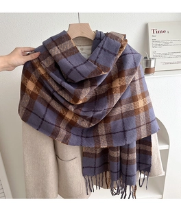 Detail of plaid scarf with tassels on wooden hanger over a beige winter coat