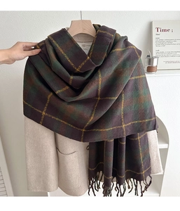 Close-up of thick plaid scarf featuring green and brown checkered texture with tassels