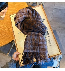 Close-up of thick plaid scarf in navy and brown with soft fringe texture detail