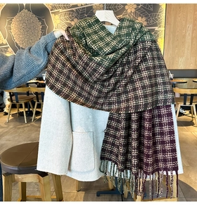 Detailed view of the thick knit plaid scarf with fringe on a beige wool coat background