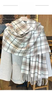Detail of plaid knit scarf with fringes paired with beige coat on a hanger