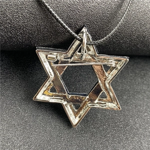 Macro view of silver star pendant back with brooch pin and woven necklace cord detail