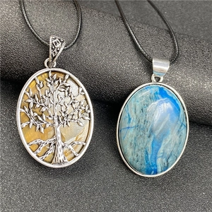 Détail de pendentifs Arbre de Vie en œil de tigre et pierre bleue sur cordons noirs