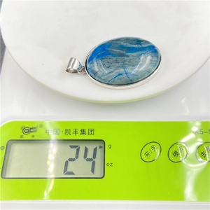 Gros plan d'un pendentif en agate bleue de 24g avec motif arbre de vie sur une balance