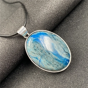 Détail du pendentif ovale en sodalite bleue avec monture argentée sur fond noir