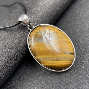 Vue macro d'un pendentif ovale en œil de tigre avec cadre argenté et cordon noir