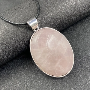 Vue macro d'un pendentif ovale en quartz rose avec monture argentée et texture naturelle