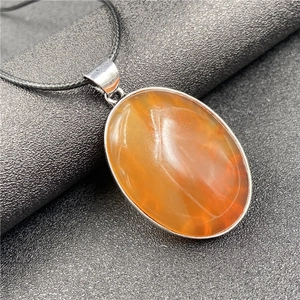 Vue macro d'un pendentif ovale en agate orange sur un cordon tressé noir élégant