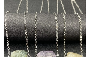 Macro detail of geometric amethyst and crystal pendants on fine silver chains