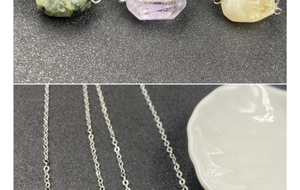Detailed macro view of amethyst and quartz hexagonal cut crystal stone pendants on silver chains