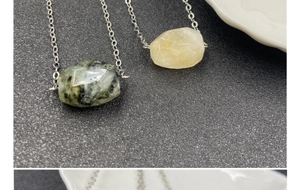 Close-up of raw amethyst and citrine crystal pendants on thin silver link chains