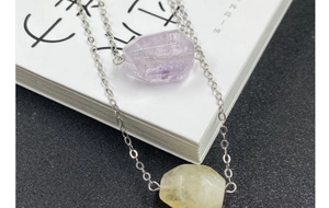 Macro shot of faceted amethyst and citrine crystal pendants on silver chains