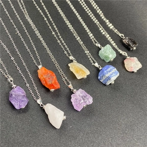 Flat lay of multiple irregular geometric raw stone crystal pendants on silver chains