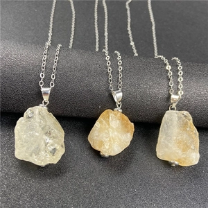 Detailed close-up of geometric natural raw stone pendants with silver-tone chain necklace
