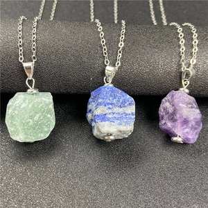 Macro detail showing three irregular natural raw gemstone pendants on silver chains
