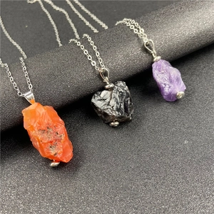 Detailed view of three irregular natural raw stone pendants in orange, black, and purple