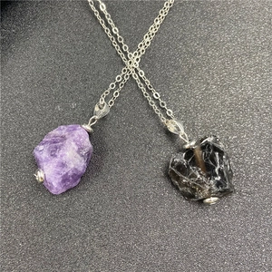Detail of natural raw purple amethyst and black stone pendants on silver link chains