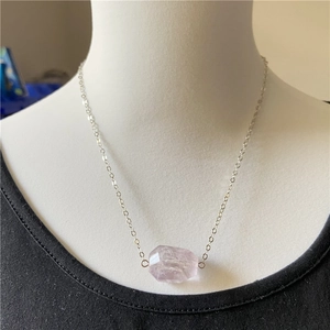 Faceted purple amethyst pendant on silver chain necklace worn by mannequin on black background