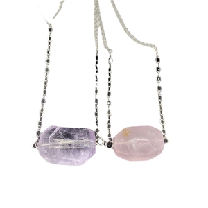 Faceted amethyst and rose quartz pendant necklaces with delicate silver chains on white