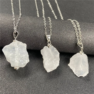 Macro shot of three natural raw white crystal pendants on silver chains and black pedestal